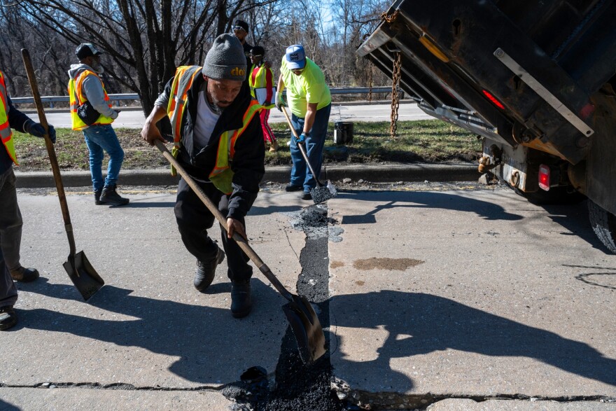A work crew fills potholes on Perring Parkway in Baltimore. Crews filled at least 32,000 potholes from late February through mid-March, and the city aims to fill another 25,000 potholes by mid-July.