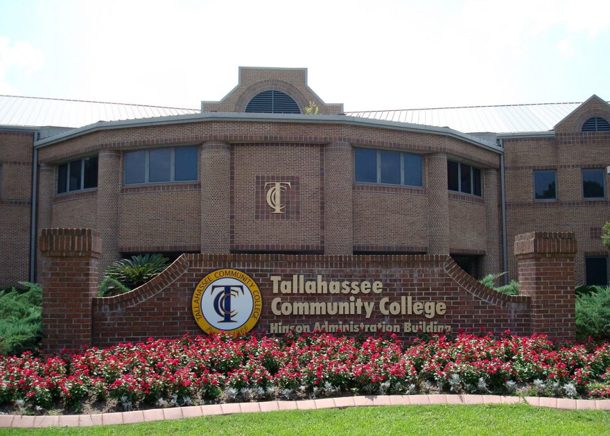 Large red building behind red flowers and a green lawn