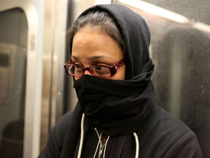 A woman on the L train in New York City last week covers her face, fearful because a doctor with Ebola rode the train days earlier. Epidemiologists say people on the subway were not at risk.