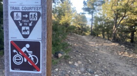 A courtesy trail marker reminds riders that e-bikes are not allowed on the trails outside of Salida. the top sign reads "Trail courtesy" with symbols indicating that bike riders must yield to pedestrians and horseback riders.