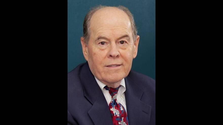 A man in suit and tie sits for a headshot.