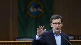 Gov. Bob Ferguson of Washington raises his hand as he talks.