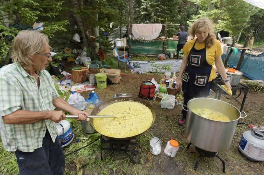 Rainbow Family members Dino, left, and Brajamohini, cook at their Sumdor Krishna Kitchen on July 4, 2022, in the Adams Park area of Colorado’s Routt National Forest. The previous day they served free meals to 1,000 people.