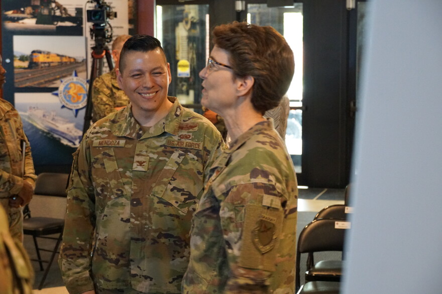 In front of a poster board detailing U.S. Transportation Command's assignment, Col. Daniel Mendoza and Gen.  Jacqueline Van Ovost talk on Monday, June 5, 2023.