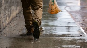 In this photo, a pedestrian walks through a water puddle on an Austin sidewalk.