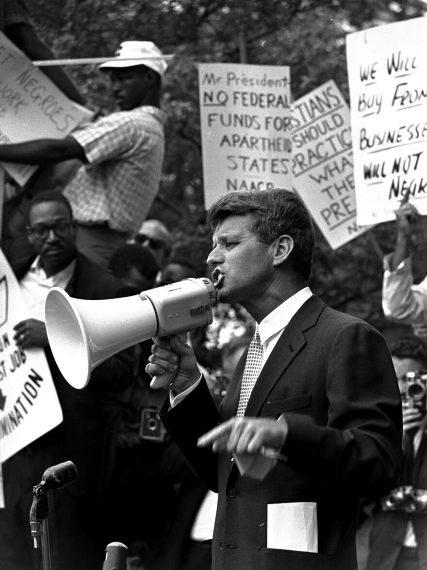 Attorney General Robert F. "Bobby" Kennedy uses a bullhorn to address a crowd of demonstrators, June 14, 1963, at the Justice Department. Four months earlier he had walked 50 miles in one day to prove to his brother John that he could do it. His march helped make extreme walking and hiking popular activities.