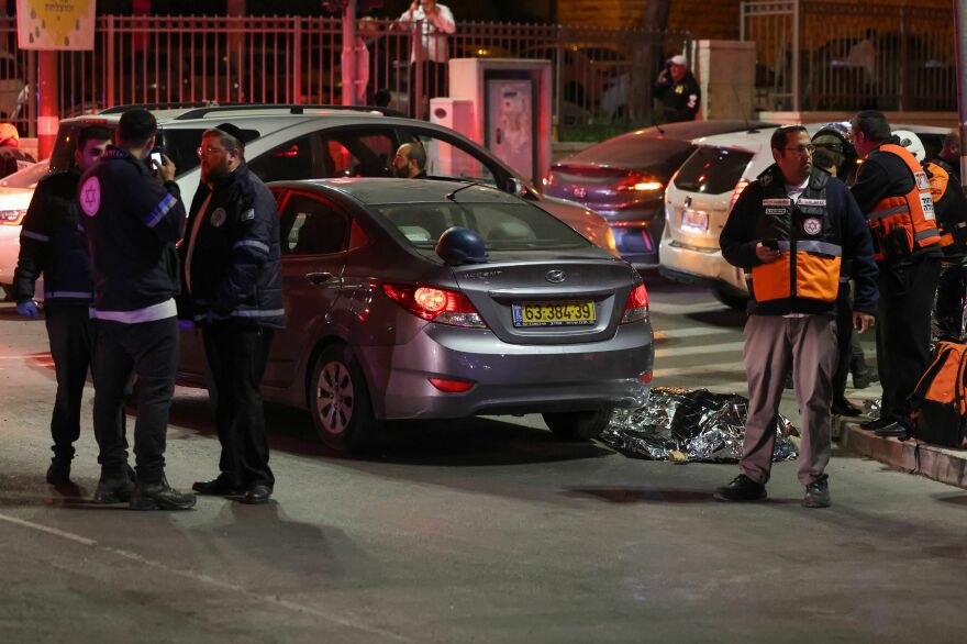 Israeli emergency service personnel and security forces stand near a covered body at the site of a reported attack in a settler neighborhood of Israeli-annexed east Jerusalem on Friday.