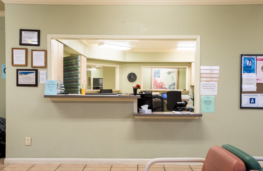 A photo of a waiting room at a doctor's office, looking from the seating area to the administrative area.