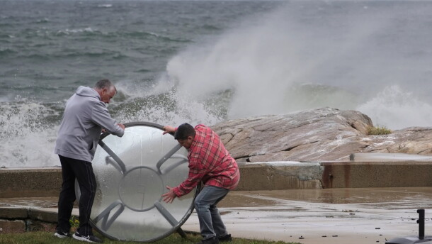 John Garrisi, left, and Gaige Graf move an outdoor table away from the shorefront during the early stages of a nor'easter storm on Friday.