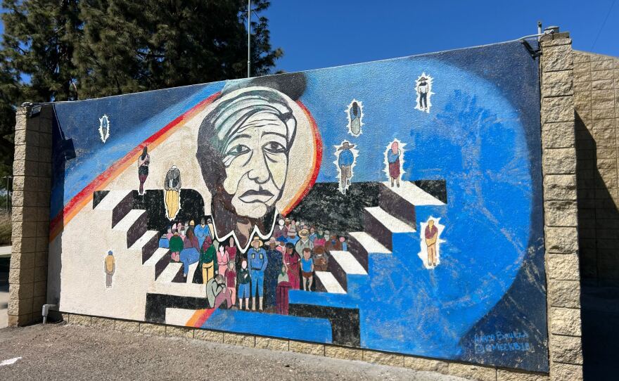 A brightly colored mural featuring a painted likeness of Cesar Chavez as well as other figures.