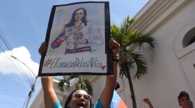 A supporter of opposition leader Maria Corina Machado holds up a poster with her image, during a rally calling for her return to the country and immediately elections in Los Teques, Venezuela, Sunday, Sept. 27, 2026. (AP Photo/Pedro Mattey)
