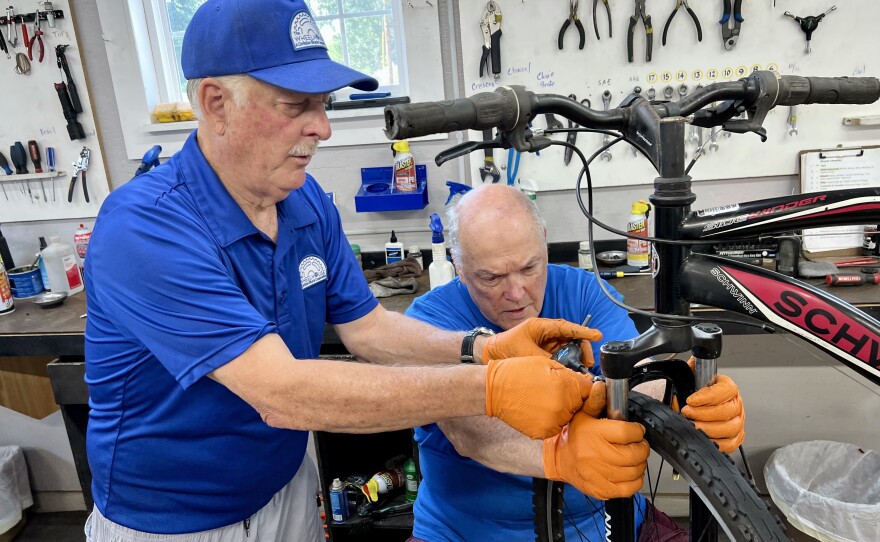 Tim Heinz works with another Wheelhouse volunteer to refurbish a donated bicycle.