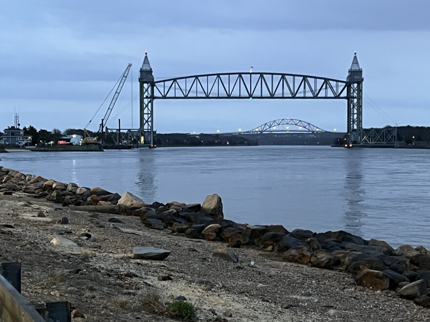 The railroad bridge over the Cape Cod Canal frames the Bourne Bridge in the distance on a cloudy evening, April 15, 2025.