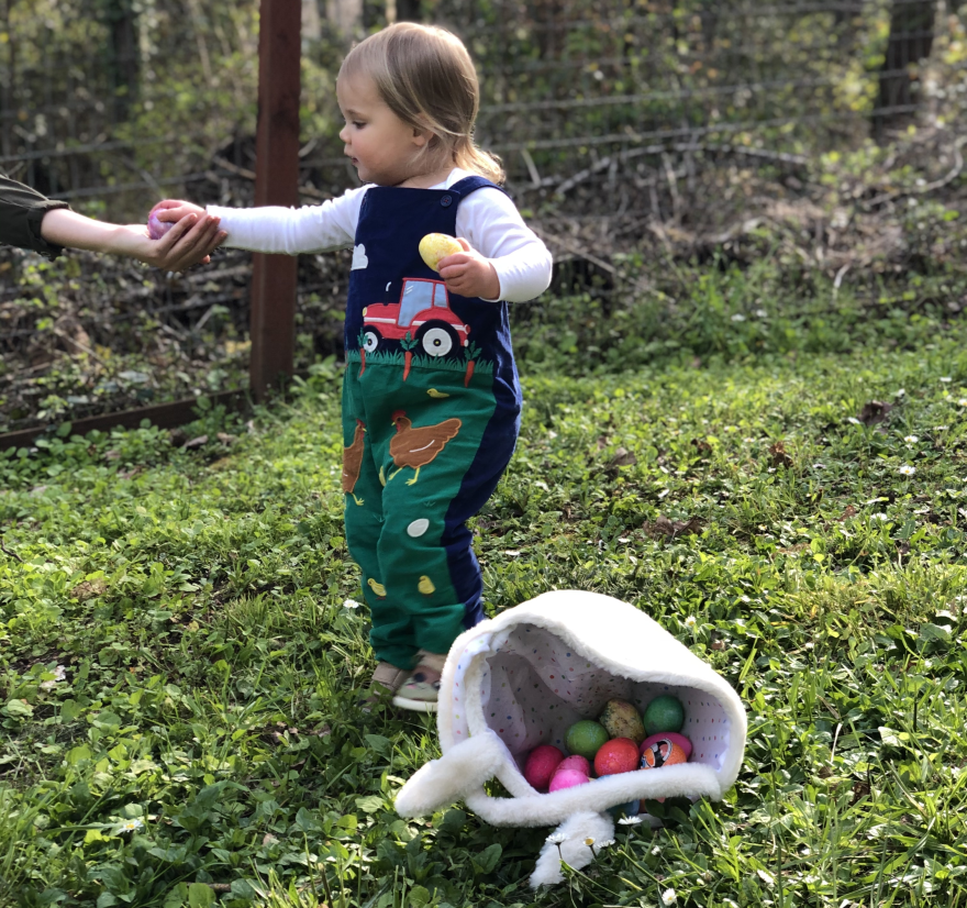 A child holding Easter eggs and an Easter basket with eggs.
