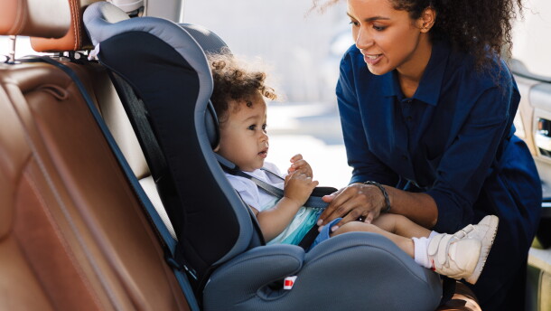 Young mother preparing baby car seat for her son