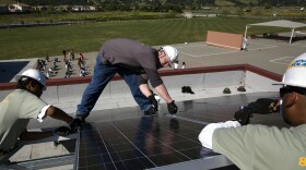 PLEASANTON, CA - APRIL 16: Employees of SPG Solar mount a photovoltaic panel onto a steel rack on top of one of seven public school rooftops on April 16, 2008 in Pleasanton, California. The rooftop solar panel array is a 186 kw system. The Pleasanton school district decided in January, 2007 to initiate a "Go Green" campaign in attempting to cut electricity costs and use renewable energy with generous state and federal tax incentives and rebates for converting to solar power. Pleasanton signed a contract with the Honeywell Corporation to buy power from the company's installed and maintained panels on all seven of the district's schools. The plan would give the city a 20% reduction in electricity charges and lock them into a 20-year fixed rate power purchase agreement with Honeywell. Surplus power kicked back into the Pacific Gas & Electric electric grid would be credited to the school district. The solar panels produce electricity in DC current which is then converted to AC current utilized inside the building with an inverter.