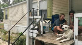 Jenna Clark, left, pets her family's pit bull, Buster, with a friend. Clark, 18, said her family will stay in their mobile home in Panacea during Hurricane Michael.