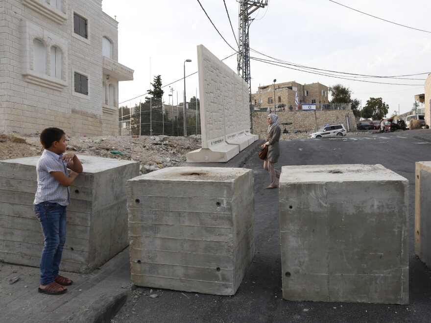 Palestinians look at a new concrete wall erected by Israeli security forces in the East Jerusalem neighborhood of Jabel Mukaber.