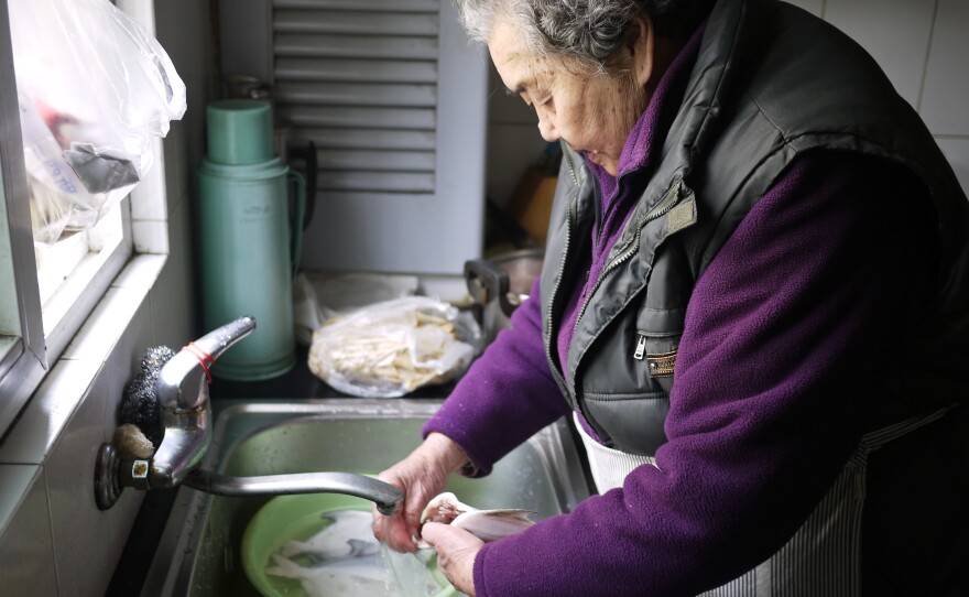 Yuan Shuizhen, 85, prepares fish and chicken feet for the Lunar New Year holiday in her garden-level kitchen.