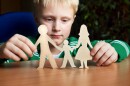 This stock photo shows a child holding a paper cutout of a family.