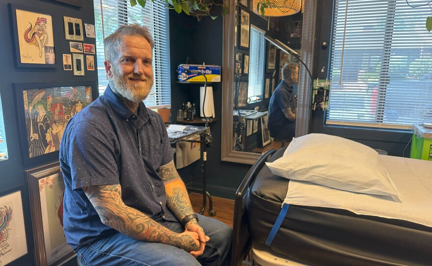 Canyon Webb sitting inside his tattoo shop, Good Neighbor Tattoo.