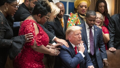 Black leaders say a prayer with President Trump as they end a meeting in the Cabinet Room of the White House in February.