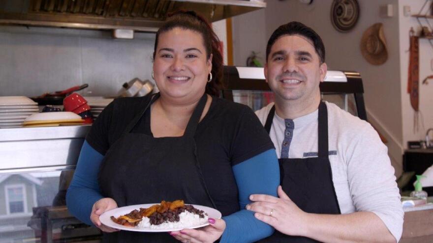  Diana Molinares and Edgar Pachon in the kitchen holding a palte of Carne Guisadan at Sabor Di Mi Tierra holding a plate of 