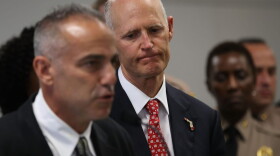 Florida Gov. Rick Scott listens as Andy Pollack, who lost his daughter Meadow Pollack, 18, during the mass shooting at Marjory Stoneman Douglas High School, speaks during a press conference at Miami-Dade police headquarters on Feb. 27, 2018 in Doral, Fla. (Joe Raedle/Getty Images)