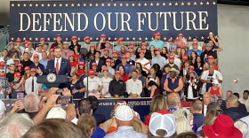 Man speaks at podium in front of a crowd