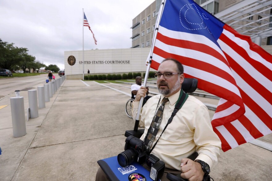 Scott Crawford, with the Mississippi Coalition for Citizens with Disabilities, waves his disability symbol American flag outside the federal courthouse in Jackson, Miss., as he and other Medicaid recipients, social service activists and supporters stage a protest outside the offices of U.S. Sen. Roger Wicker, R-Miss., Thursday, June 29, 2017, in Jackson, Miss. About 35 participants began the morning with a protest at U. S. Sen. Thad Cochran's office, and later that morning met with Wicker's staff to express their concern on the Senate's version of the overhaul of the health plan. (Rogelio V. Solis/AP)