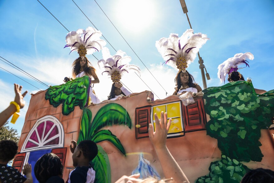 The Maids of Zulu toss "throws" or items to spectators waiting along Orleans Avenue during the Krewe of Zulu parade.