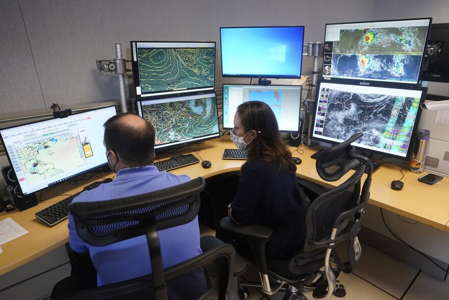 Daniel Brown, left, senior hurricane specialist, and hurricane specialist Lisa Bucci track the remnants of Hurricane Agatha, June 1, 2022, at the National Hurricane Center in Miami.