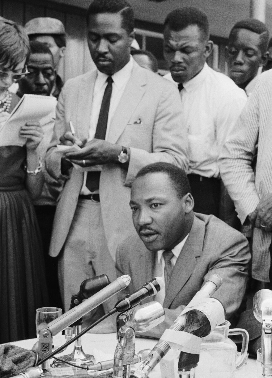 Clarence B. Jones, legal adviser to Martin Luther King Jr., takes notes behind King at a press conference regarding in Birmingham, Ala., in February 1963.