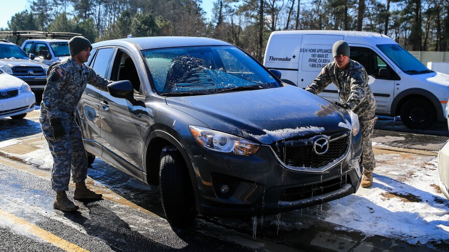 Staff Sgt. Anthony Orsi, left, and Staff Sgt. Raymond Novak of the Army National Guard helped Lauren Gates (in vehicle) retrieve her car Thursday from the Cumberland Boulevard exit ramp along I-75 North in Atlanta. Guard members and police were working to reunite drivers with more than 2,000 cars.