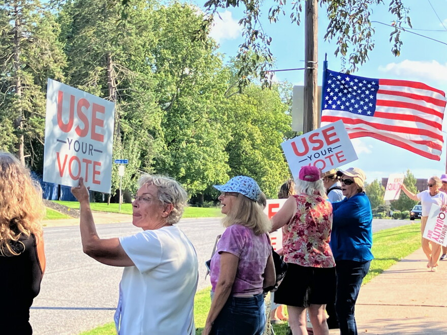 Quad Cities National Organization for Women president Leslie DuPree (left) holds a "Use Your Vote" sign up at the SAVE Act protest along Brady Street, Wednesday, Aug. 26, 2026.