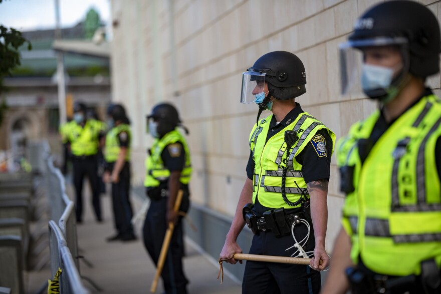 Boston police officers with batons lined up outside the District B-2 station in Roxbury before a protest on May 31. (Jesse Costa/WBUR)