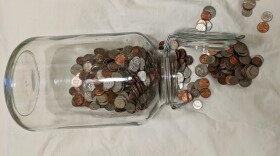 Coins spilling from an overturned glass jar.