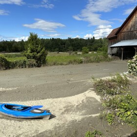 Barn and kayak sitting on a bed of river silt