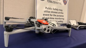 A grey drone sits on a blue table