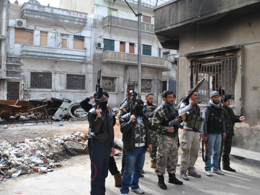 Syrian rebels gather in front of a Syrian government military vehicle that was destroyed during clashes in the central city of Homs on Feb. 23. The city has been the scene of the heaviest fighting in recent weeks.