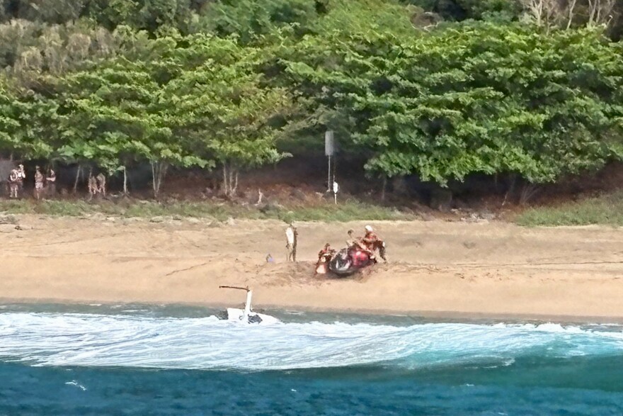 Kauaʻi Ocean Safety members and other people assist individuals after an Airborne Aviation tourist helicopter crash on Kalalau Beach on Kauaʻi, Hawaiʻi, on March 26, 2026. (U.S. Coast Guard photo. Courtesy Station Kauaʻi)
