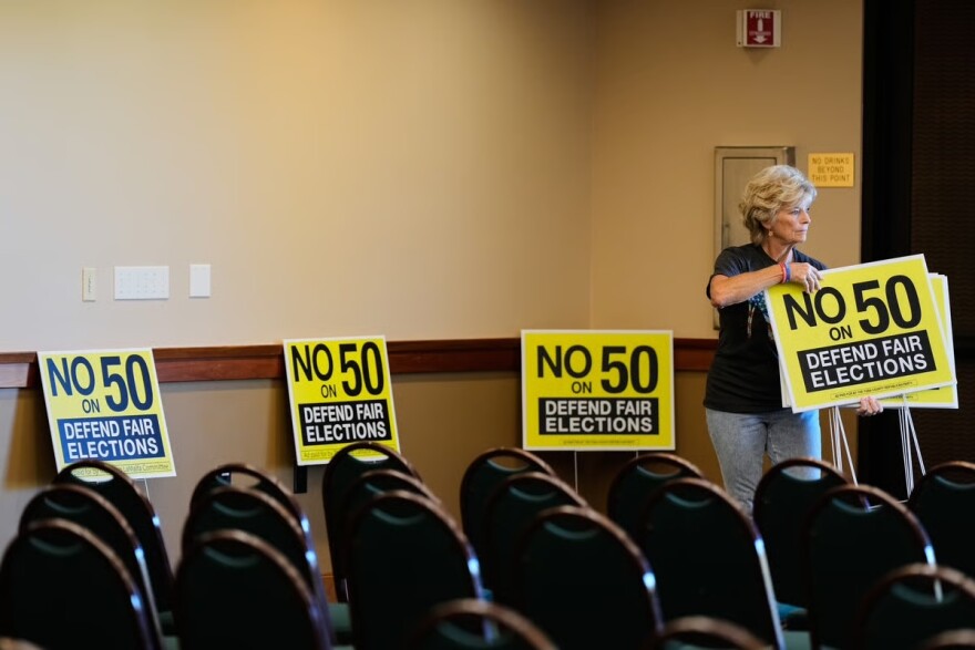 Brenda Haynes places signs throughout a conference room before a No on Prop 50 rally in Redding, Calif., Tuesday, Oct. 21, 2025.