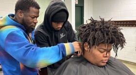 Teacher Johnny Mallary shows senior Thomas Young how to do a fade on his classmate, senior Rashad Mace.