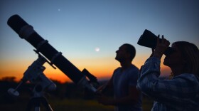 Couple stargazing together with a astronomical telescope.