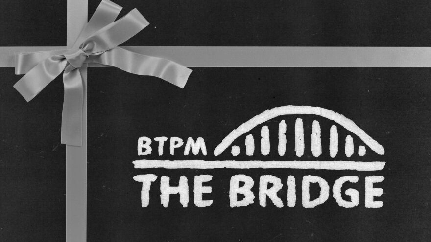 Black speckled background and a silver bow, tied in the top left corner. In the bottom right corner the logo for BTPM The Bridge