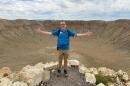 Hikers can walk to the bottom of Meteor Crater in Northern Arizona. Guide Tyler Johnson speaks to a group at the top of the mile-wide hole that was formed 50,000 years ago when a meteorite struck the earth. (Peter O’Dowd/Here & Now)