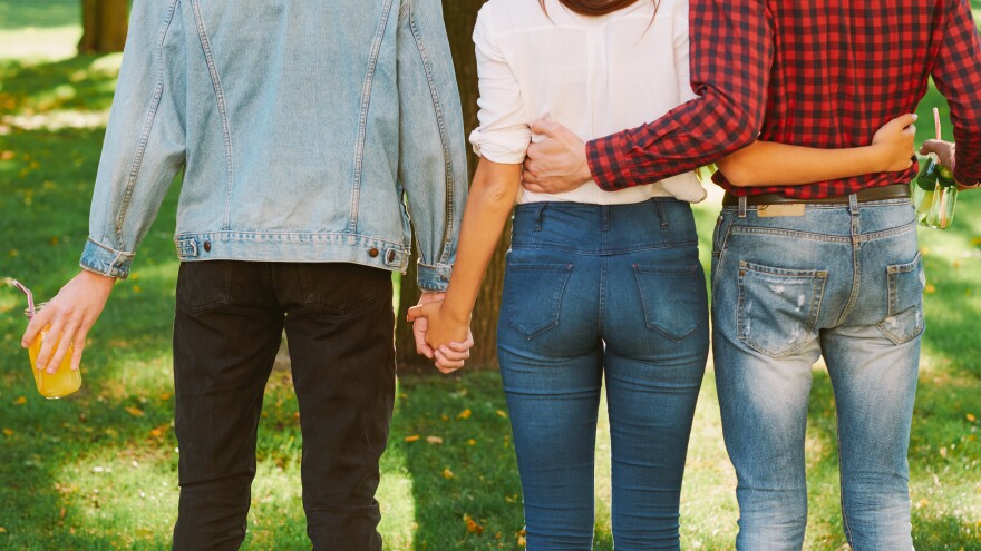 Polyamorous relationship. Love affection partnership. Woman standing with two guys in nature park.