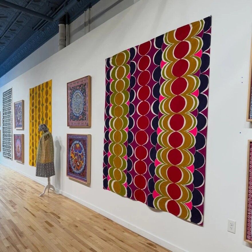 Framed artwork and textiles on a white wall