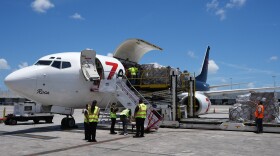 People load pallets containing food and hygiene kits into a cargo plane