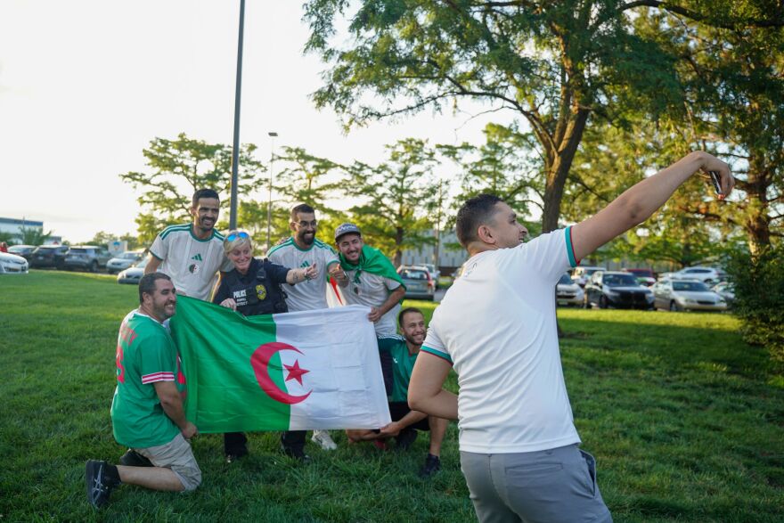 Detective Meghan Bardell and Algerian fans pose for a selfie with the Algerian National flag in Lawrence, Kansas.